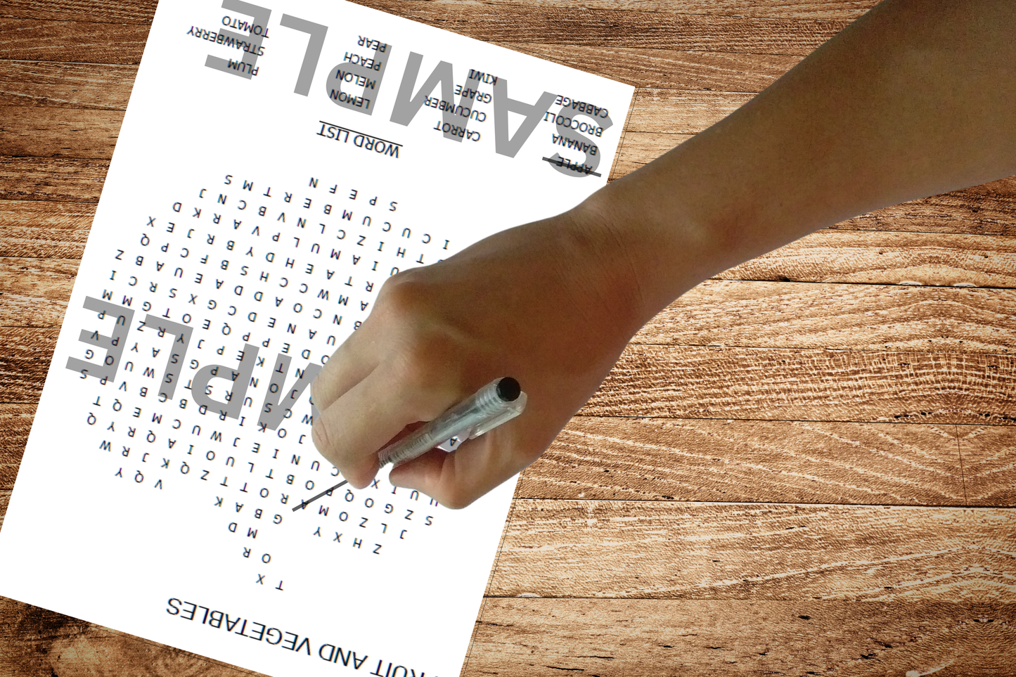 Fruit and Vegetables- themed Children's Word Search on a wooden table with a child's hand solving the puzzles