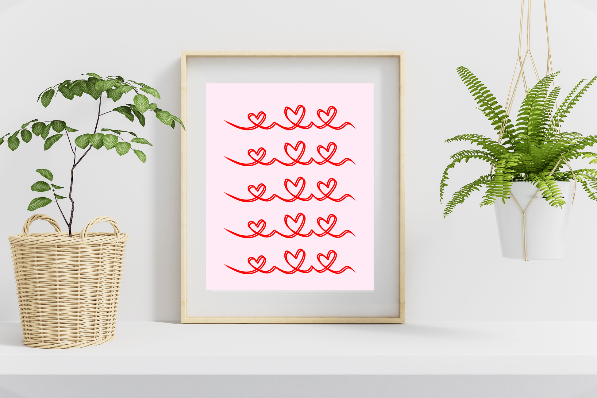 Framed artwork with red heart patterns on a white wall, flanked by plants.