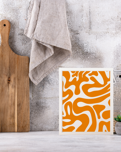 Orange textures artwork framed on a kitchen counter next to a wooden chopping board