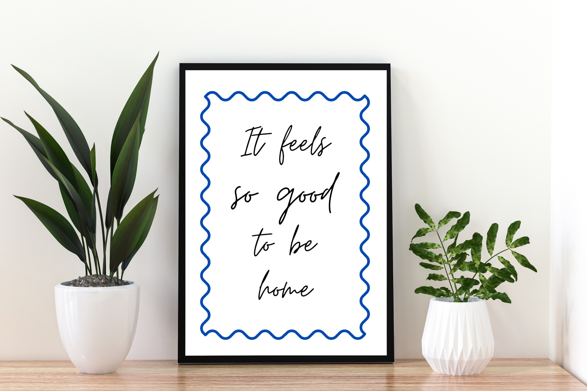 High-definition cobalt blue quote print "It feels so good to be home" framed in a clean and modern hallway space, perfect for uplifting everyday décor.